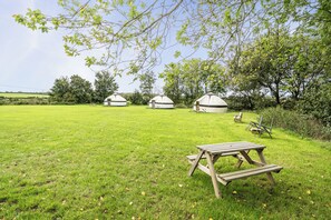 A grassy field with yurts and a picnic table.