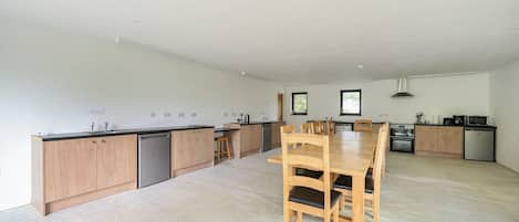 A spacious kitchen with wooden cabinets, a central island, and a dining table with chairs.