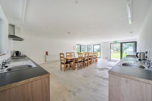 A modern kitchen with a central island, wooden chairs, and a large window providing a view of the outdoors.
