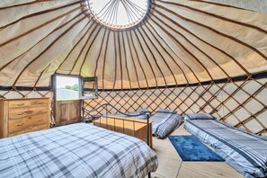 A yurt with a round ceiling, wooden furniture, and a bed with a plaid bedspread. - Yurt Sleeps 5 - Dogs Welcome - Bbq (Bodmin)