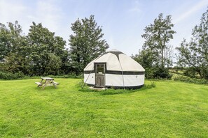 A yurt with a door and a small porch, surrounded by a grassy field and trees. - Yurt Sleeps 5 - Dogs Welcome - Bbq (Bodmin)