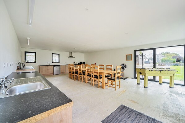 A modern kitchen with a dining area, a foosball table, and a view of the outdoors. - Yurt Sleeps 5 - Dogs Welcome - Bbq (Bodmin)
