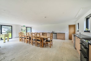 Una cocina amplia con armarios de madera, horno empotrado y comedor con mesa y sillas de madera.