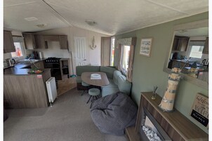A compact RV interior with a kitchenette, a seating area, and a fireplace.