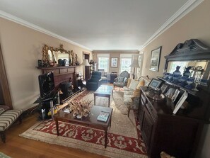 A traditional living room with a fireplace, a sofa, a coffee table, and a bookshelf.