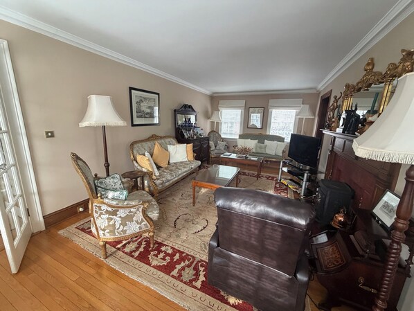 A living room with a sofa, armchairs, a coffee table, and a television.