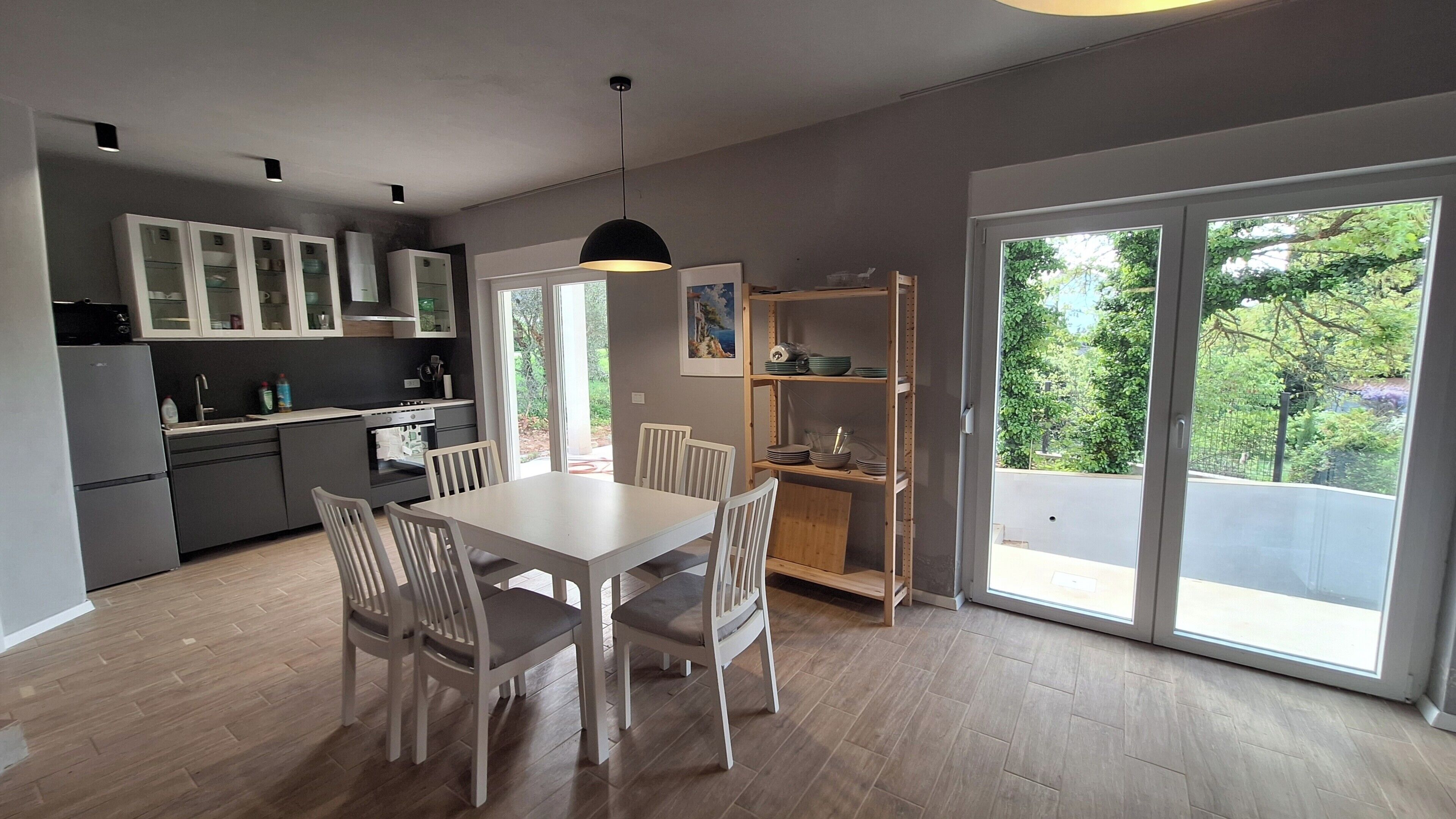 Eine moderne Küche mit Essbereich, großen Fenstern und Blick auf Grünflächen.