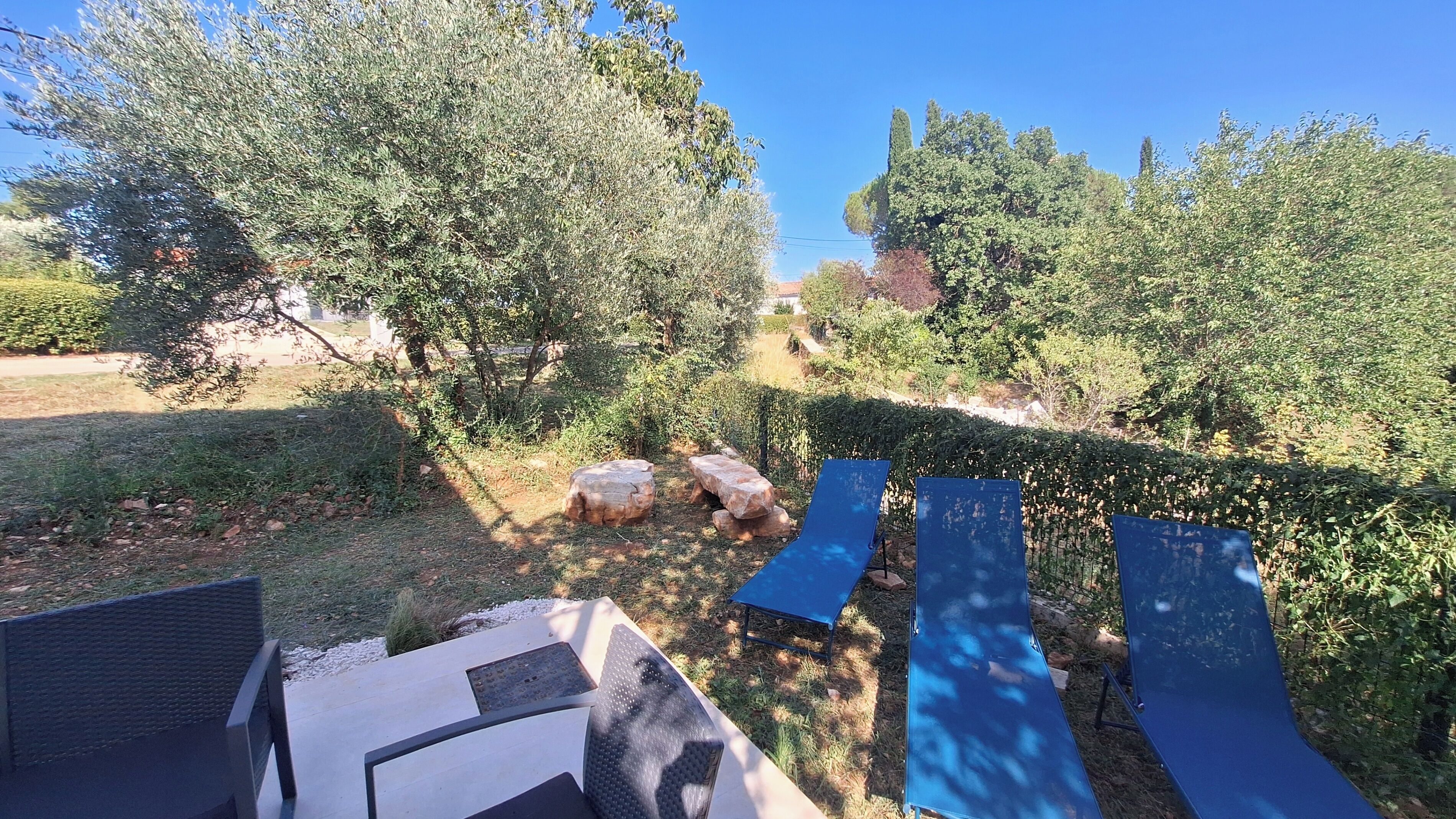 Ein Garten mit einer Sitzgelegenheit, einer blauen Rutsche und einem Weg.
