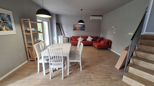 Ein Essbereich mit Tisch und Stühlen, ein rotes Sofa und eine Treppe.