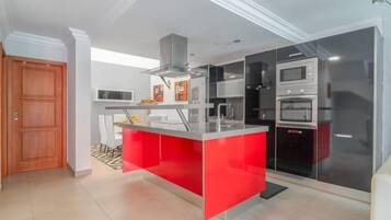A modern kitchen with a red island, built-in appliances, and a wooden door.