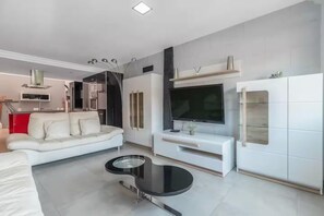 Ein modernes Wohnzimmer mit einer Couch, einem Couchtisch, einem Fernseher und einem Schrank.
