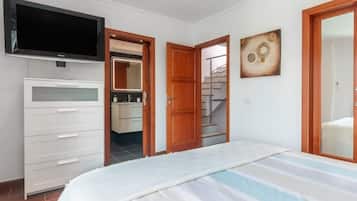 A bedroom with a bed, a TV, a wardrobe, a bathroom, and a staircase.