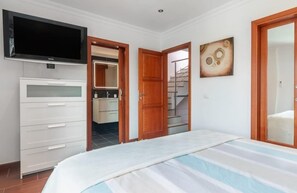 Ein Schlafzimmer mit Bett, Fernseher, Kleiderschrank, Badezimmer und einer Treppe.