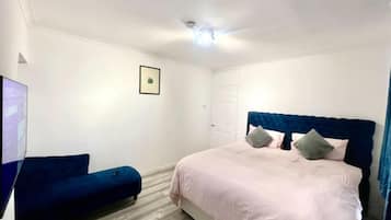 A bedroom with a bed, a blue sofa, a white door, and a ceiling light.