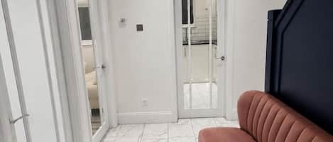A modern interior with a sofa, a door leading to a bathroom, and a tiled floor.