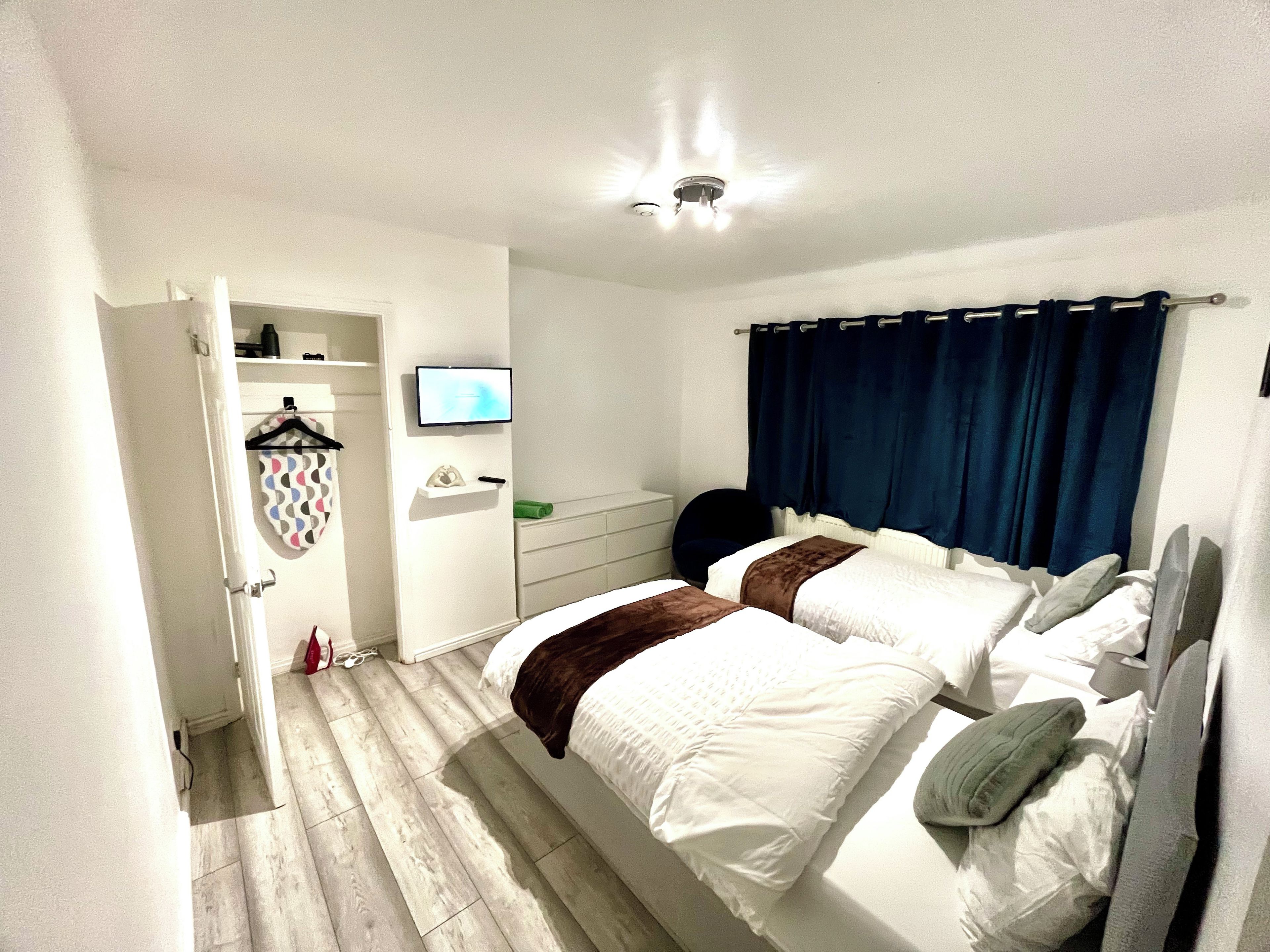 A bedroom with two beds, a television, a wardrobe, and a bathroom.