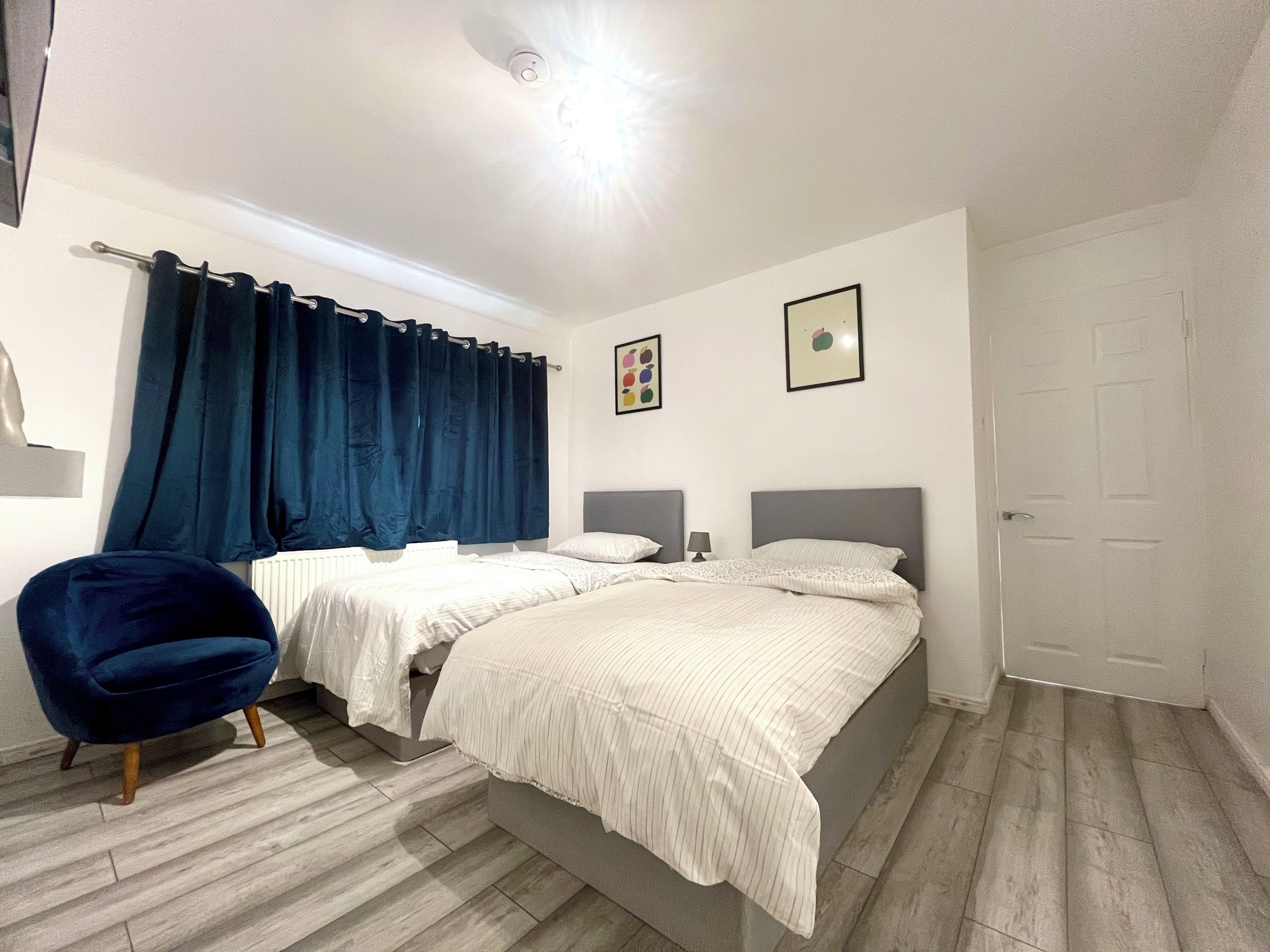 Un dormitorio con dos camas, una silla y una puerta.