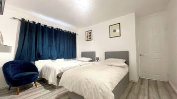 Un dormitorio con dos camas, una silla y una puerta.