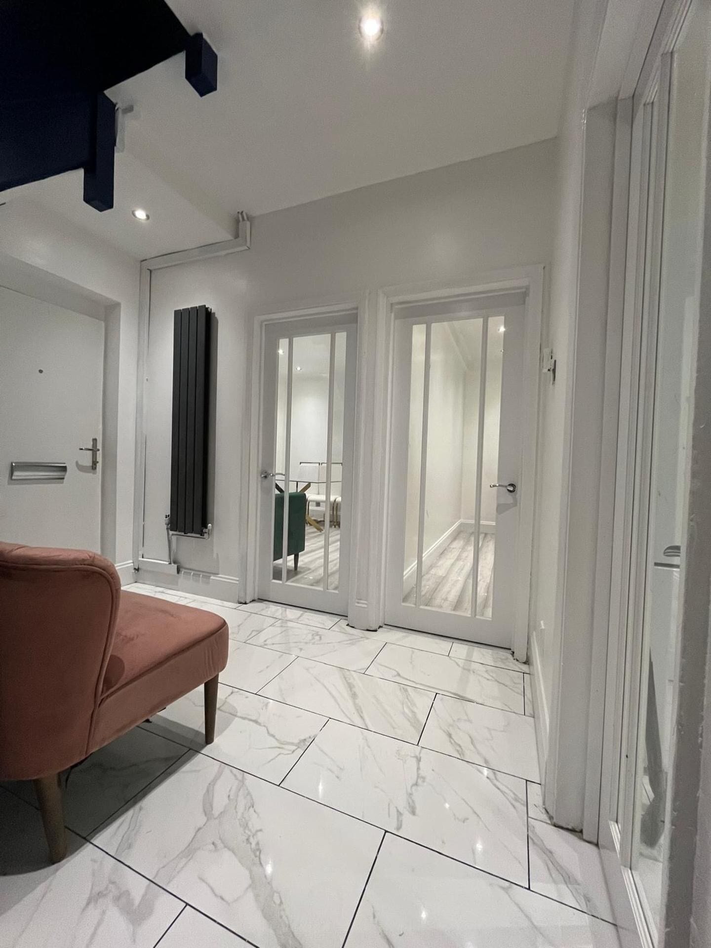 A room with a bench, white walls, and a marble floor.