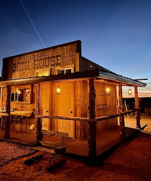 A rustic wooden building labeled 'Cane Beds Corrall Bath House' with a porch and lanterns.