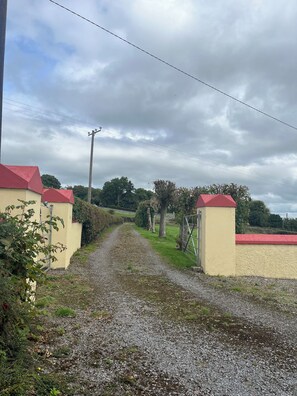 A gravel driveway leading to a gated entrance with a red roof.