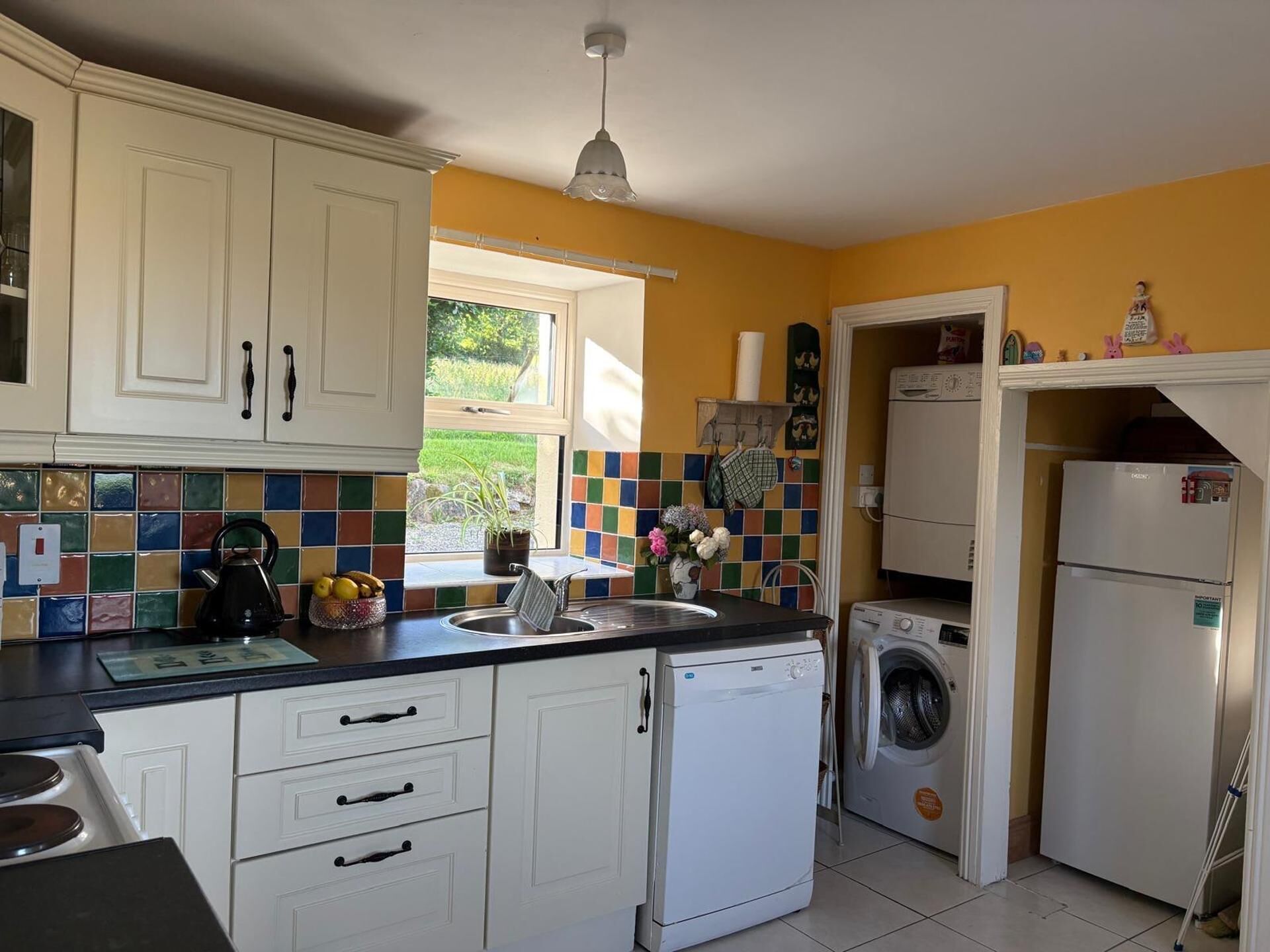 A compact kitchen with white cabinets, a tiled backsplash, a washing machine, and a refrigerator.