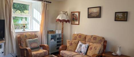 A living room with a sofa, armchairs, a coffee table, a television, and a lamp.