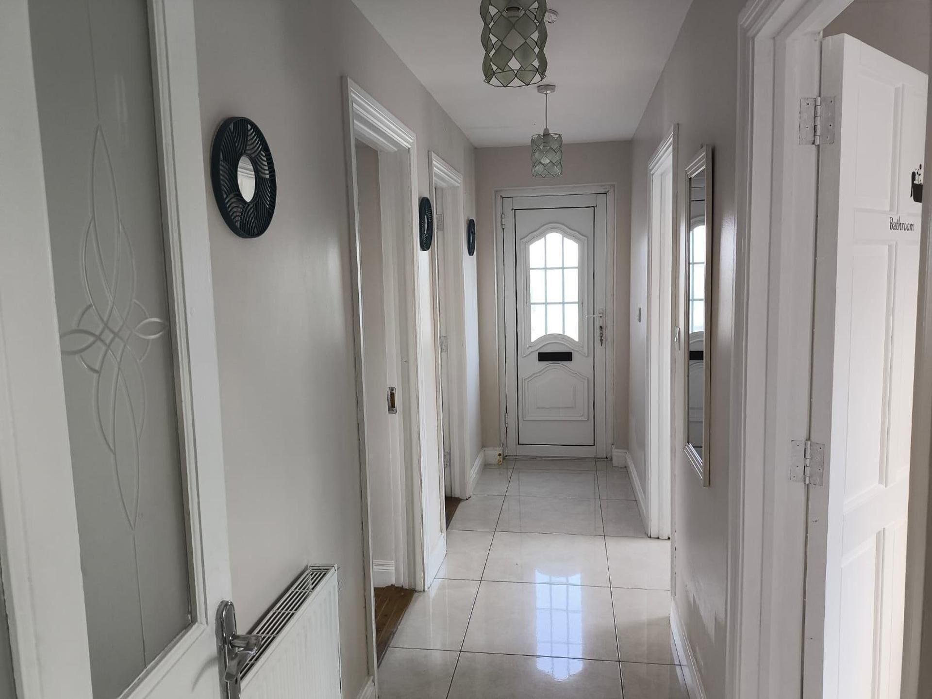 A hallway with white doors, a radiator, and a light fixture.