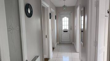 A hallway with white doors, a radiator, and a light fixture.