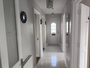 Un pasillo con puertas blancas, un radiador y una lámpara.