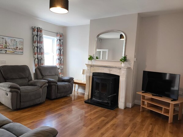 Una sala de estar con chimenea, televisor y dos sofás.