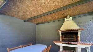 Un patio al aire libre con una parrilla de ladrillo, una mesa redonda y cuatro sillas.
