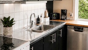 A modern kitchen with black cabinets, stainless steel appliances, and a window with a view of greenery.
