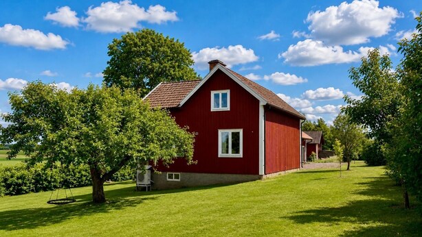 Et rødt hus med skråt tag, omgivet af en velplejet græsplæne og træer.