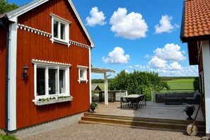 A red wooden house with a deck, a pergola, and a view of a green field. - House With 8 Beds in Fornasa (Fornåsa)