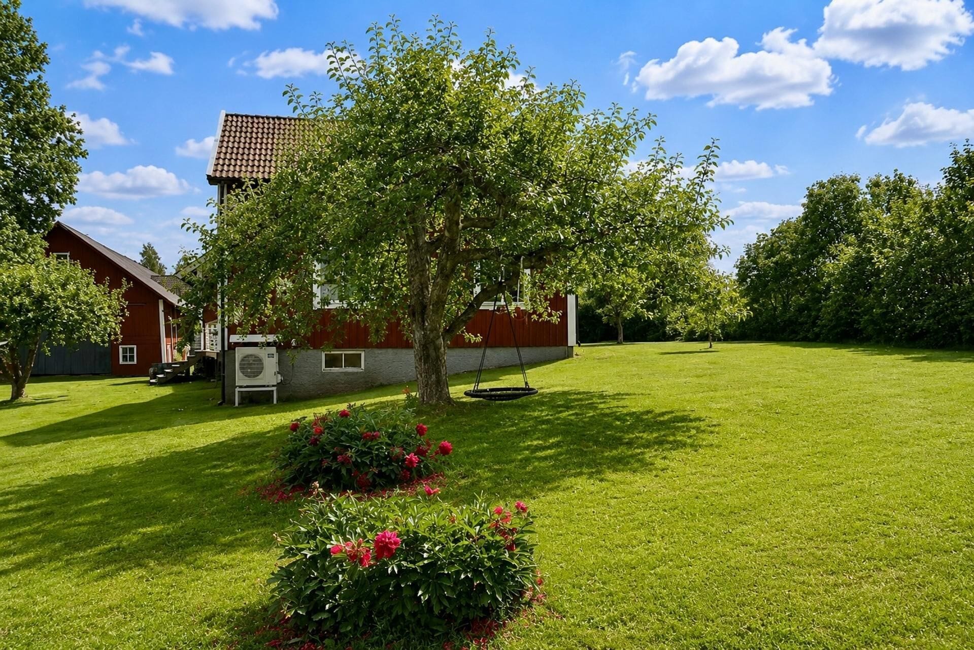 A residential property with a red barn, a lawn, and a swing set.