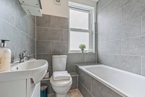 A bathroom with a white sink, toilet, and bathtub.
