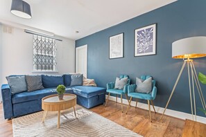 A modern living room with a blue sofa, two armchairs, a coffee table, and a floor lamp.