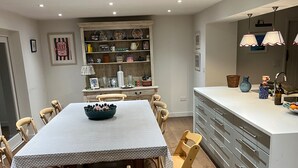A dining area with a table, chairs, and a kitchen counter. - Riverside Cottage Sleeps 8 With Parking (Marlborough)
