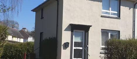 A two-story building with a flat roof, a front door, and a small porch area.