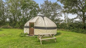 Una tienda de una sola habitación con una puerta y una pequeña mesa en un campo cubierto de hierba.