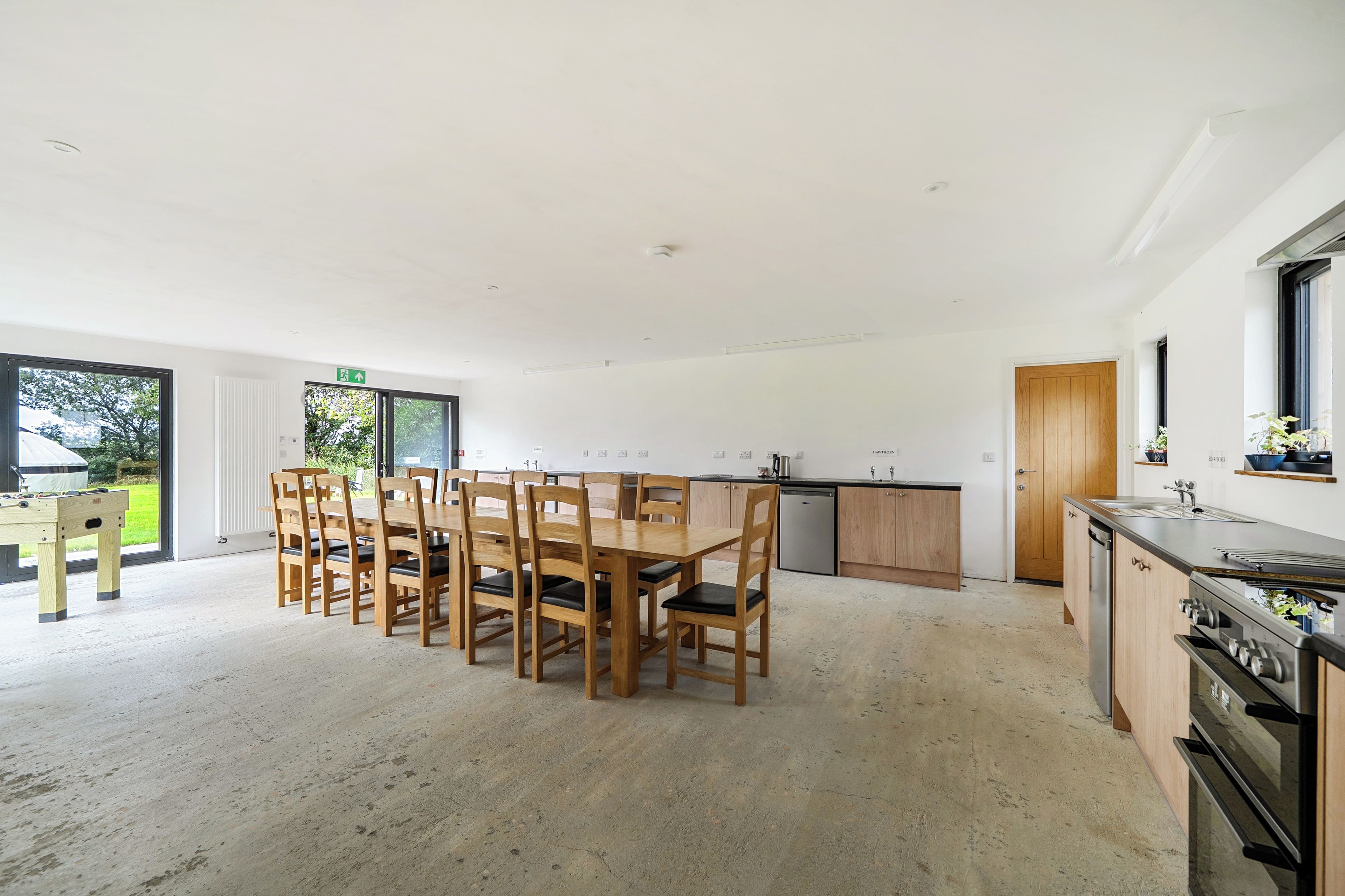 A spacious kitchen with wooden cabinets, a dining table with chairs, and a large window.