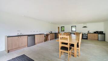 A modern kitchen with wooden cabinets, a central island, and a dining table with chairs.