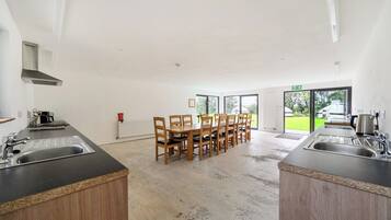 Una cocina moderna con una mesa de comedor central, sillas de madera y dos lavamanos.