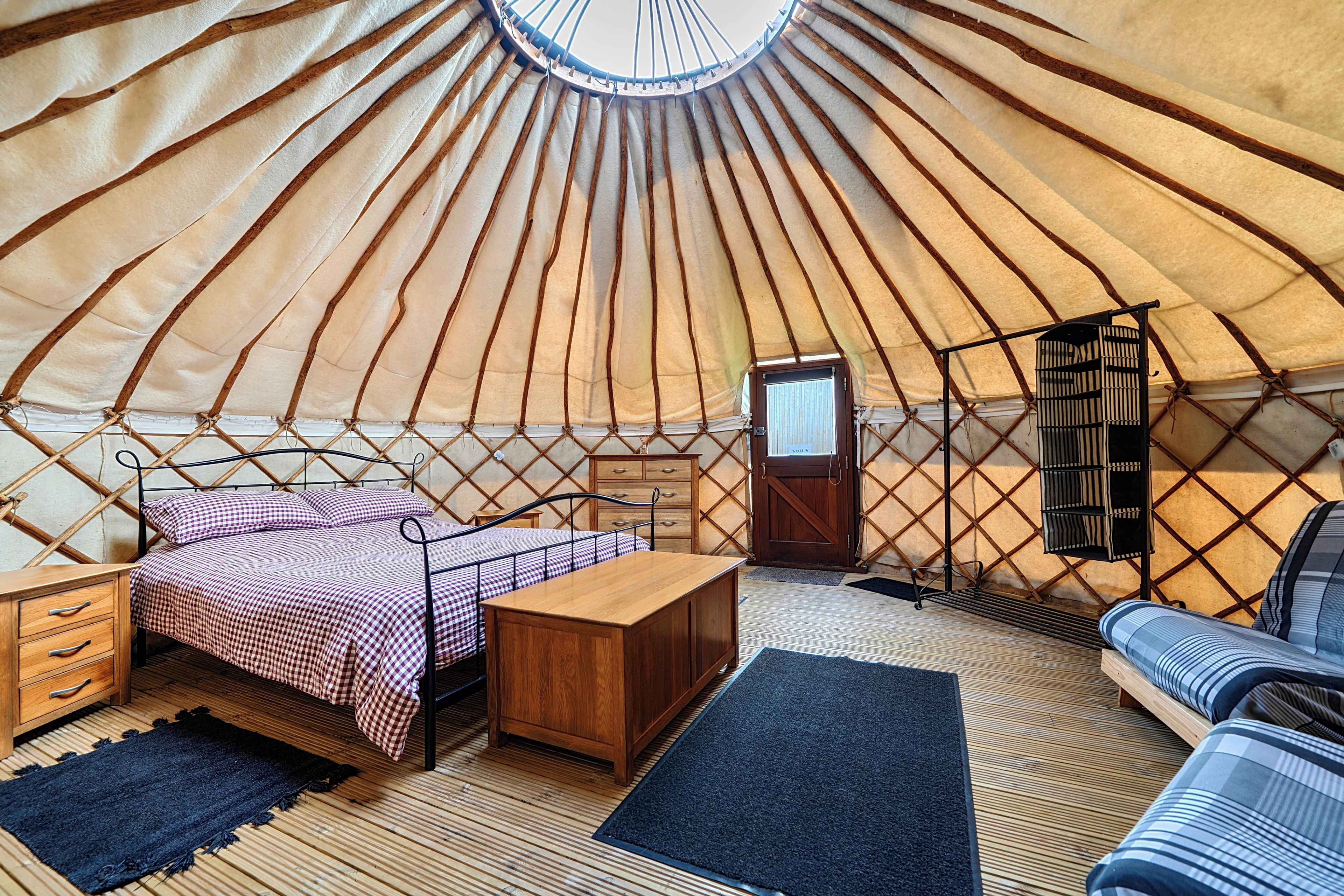 Interno di una yurta con un letto, mobili in legno e un tavolino.