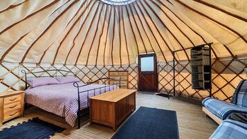 Interno di una yurta con un letto, mobili in legno e un tavolino.