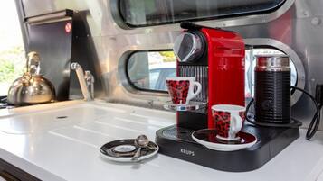 Una cafetera portátil con dos tazas sobre un lavamanos.