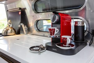 Una cafetera portátil con dos tazas sobre un lavamanos.