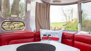Un canapé en cuir rouge avec un coussin blanc orné d’un motif représentant un véhicule aux couleurs rouge et blanche.