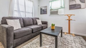 A modern living room with a grey sofa, a small table, and a decorative plant. - Coffield (Killeen)